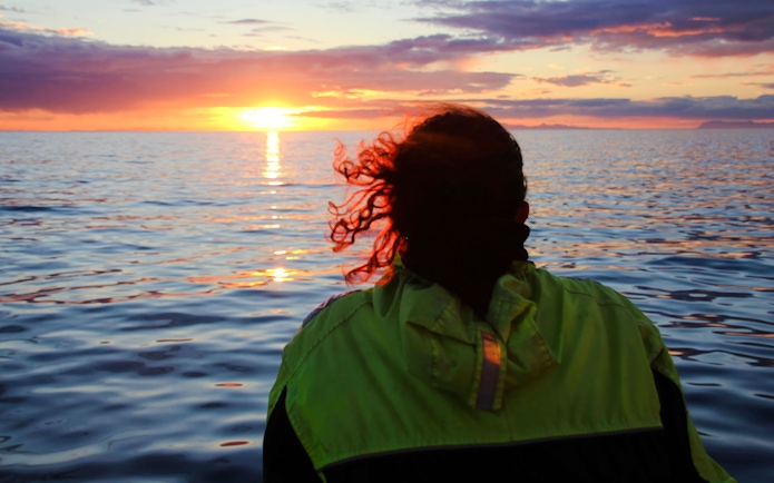 Person on a boat watching sunset over ocean during Reykjavik cruise.