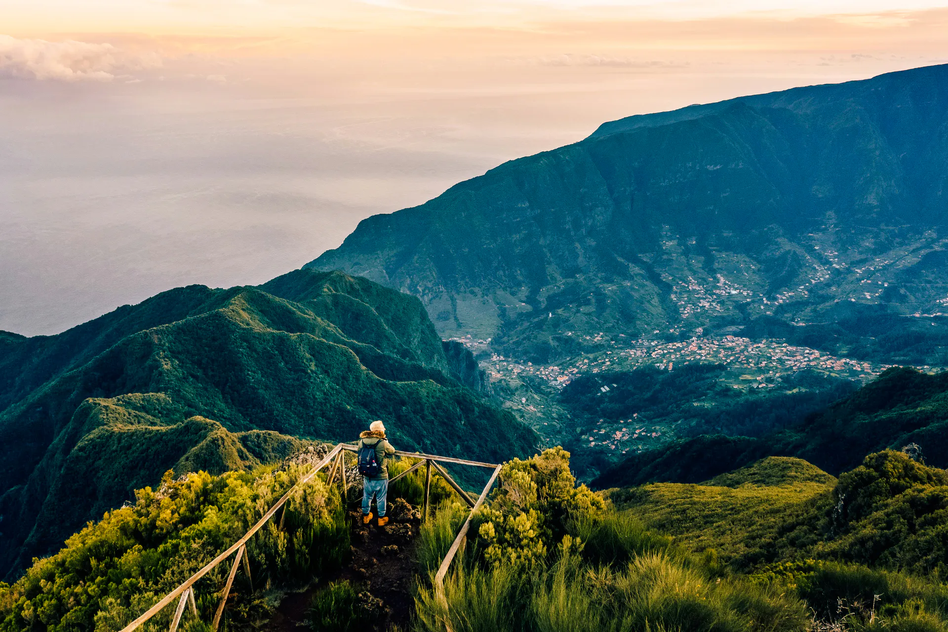 Hiker overlooking lush mountains and valley in Madeira, Portugal.
