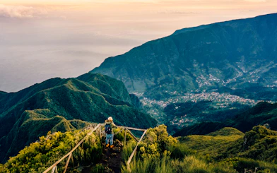 Hiker overlooking lush mountains and valley in Madeira, Portugal.