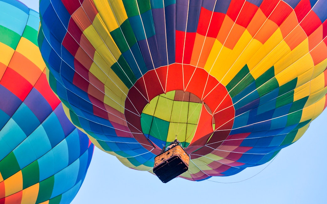 Colorful hot air balloons ascending against a clear sky.