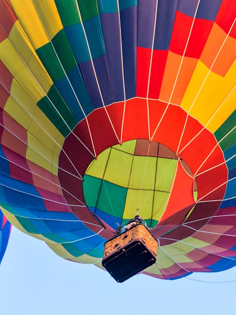 Colorful hot air balloons ascending against a clear sky.