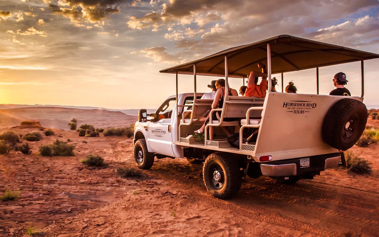 Tour group in an open vehicle exploring Secret Antelope Canyon at sunset.