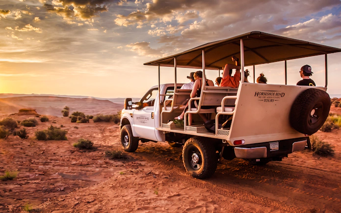 Tour group in an open vehicle exploring Secret Antelope Canyon at sunset.