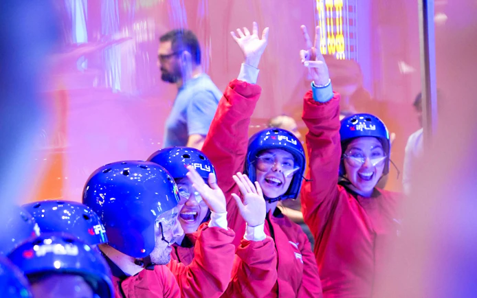 Participants in helmets and suits enjoying indoor skydiving at iFLY Quest.