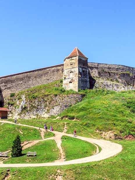 Medieval fortress on a hill with tourists walking, near Bran Castle, Romania.