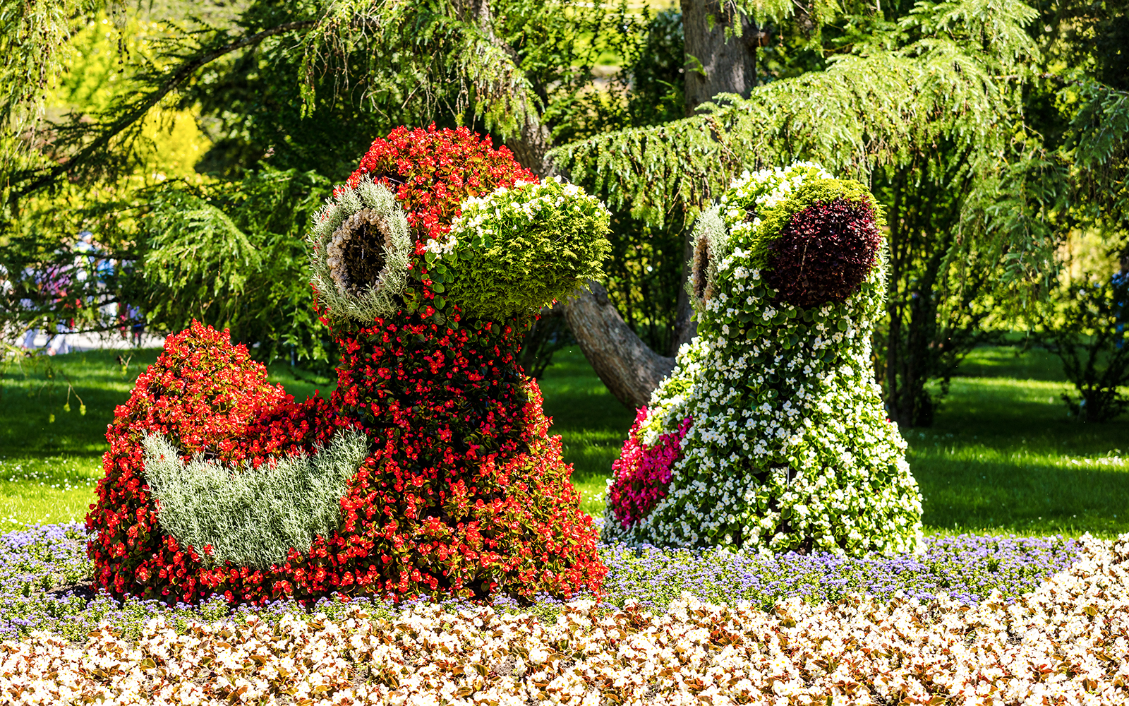 Floral sculptures on Mainau Flower Island, Germany, featuring vibrant red and green blooms.