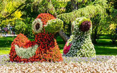 Floral sculptures on Mainau Flower Island, Germany, featuring vibrant red and green blooms.
