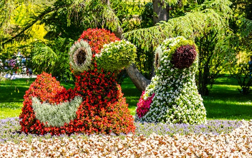 Floral sculptures on Mainau Flower Island, Germany, featuring vibrant red and green blooms.