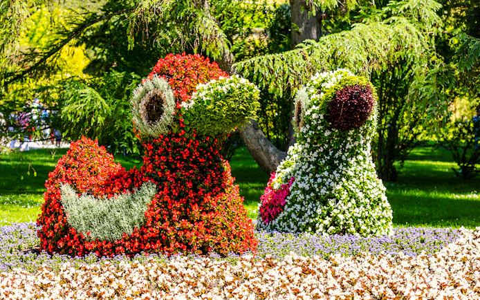 Floral sculptures on Mainau Flower Island, Germany, featuring vibrant red and green blooms.