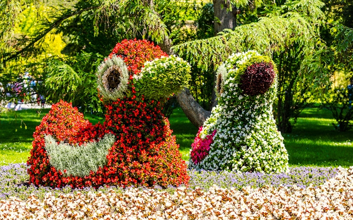 Floral sculptures on Mainau Flower Island, Germany, featuring vibrant red and green blooms.
