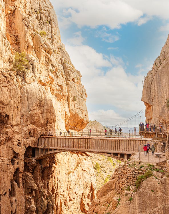 Visitors walking along the narrow path of Caminito Del Rey in Malaga, surrounded by steep cliffs.