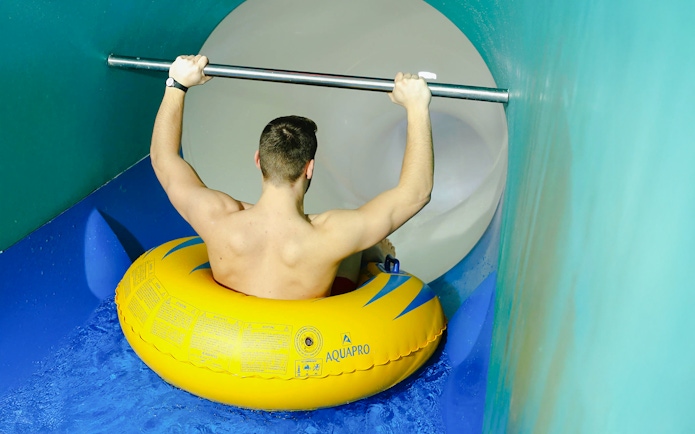 Person on yellow inflatable entering Pulsar slide at Therme Bucharest.