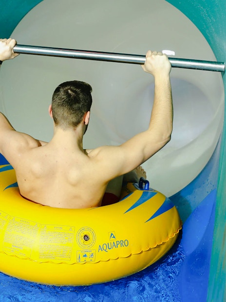 Person on yellow inflatable entering Pulsar slide at Therme Bucharest.
