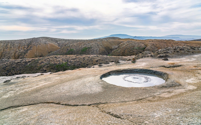 Mud volcano crater in Gobustan, Baku with surrounding arid landscape.