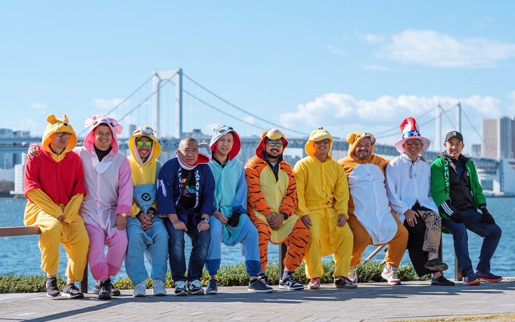 People in colorful costumes on Tokyo Shibuya Street Go-Kart Experience with cityscape background.