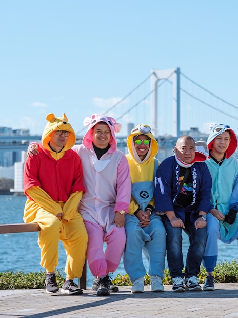 People in colorful costumes on Tokyo Shibuya Street Go-Kart Experience with cityscape background.