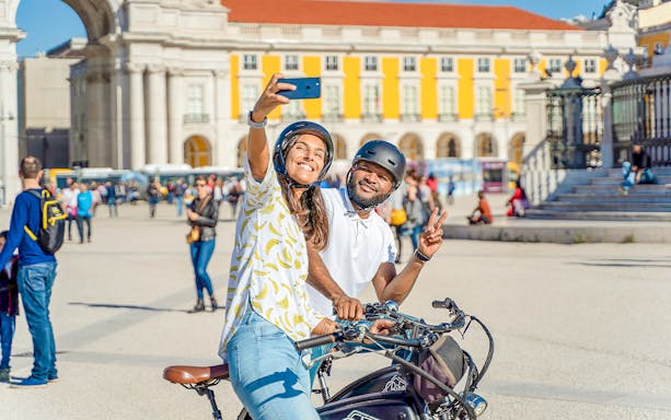 Tourists on electric bikes taking selfie at Praça do Comércio, Lisbon, Portugal.
