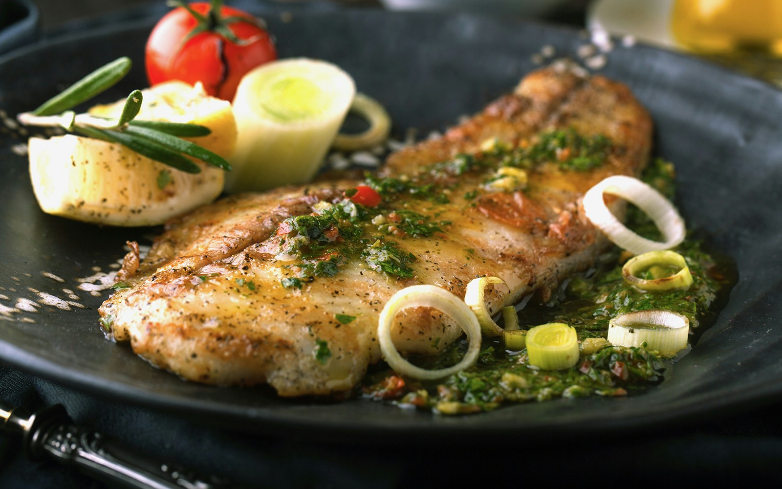 Pan roast cod dish at Howies Restaurant, garnished with vegetables and sauce.