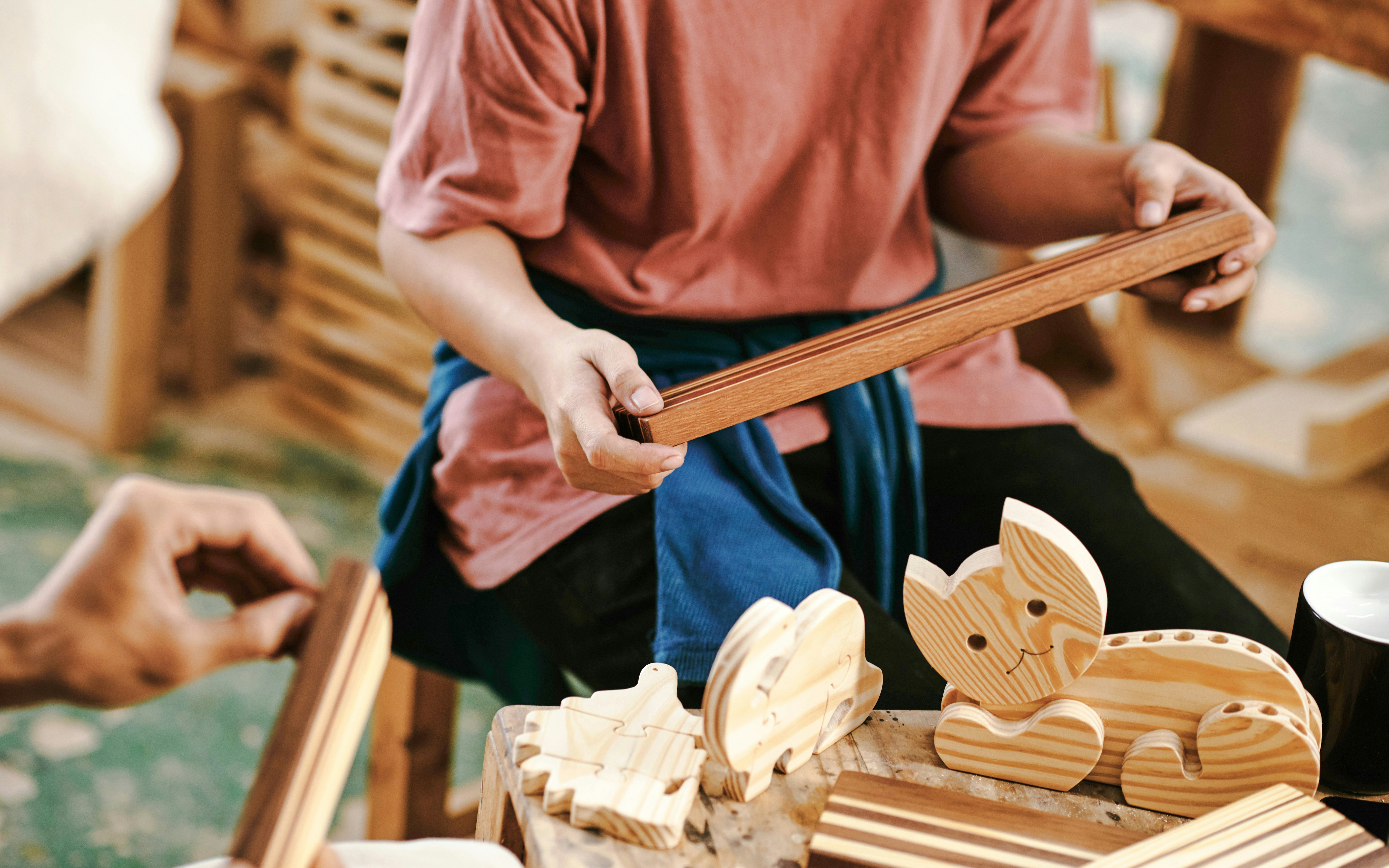 Person crafting wooden toys in Amsterdam workshop.