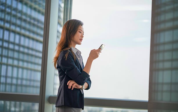 Person using smartphone in modern building, illustrating Korea 4G Tourist eSIM usage.