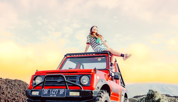 Bali jeep tour participant on vehicle at Mount Batur sunrise.