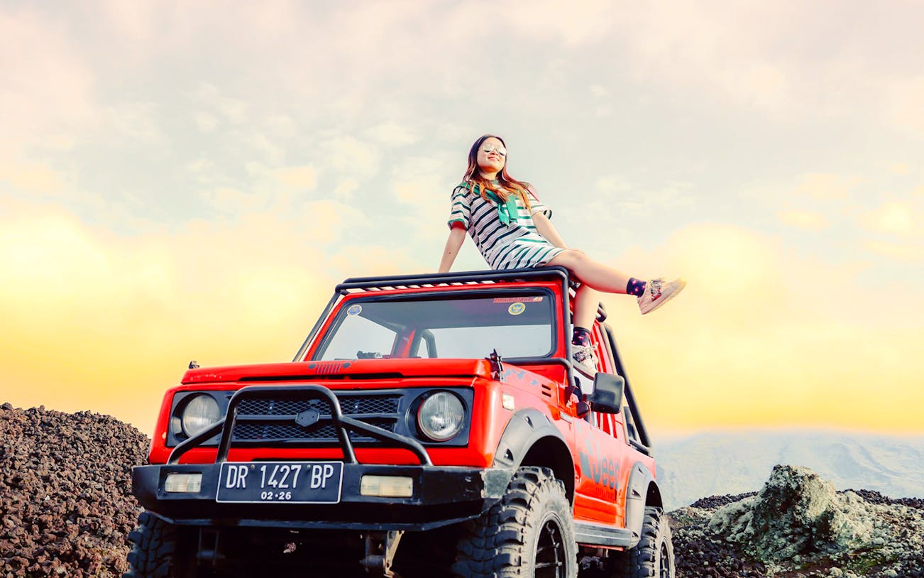 Bali jeep tour participant on vehicle at Mount Batur sunrise.