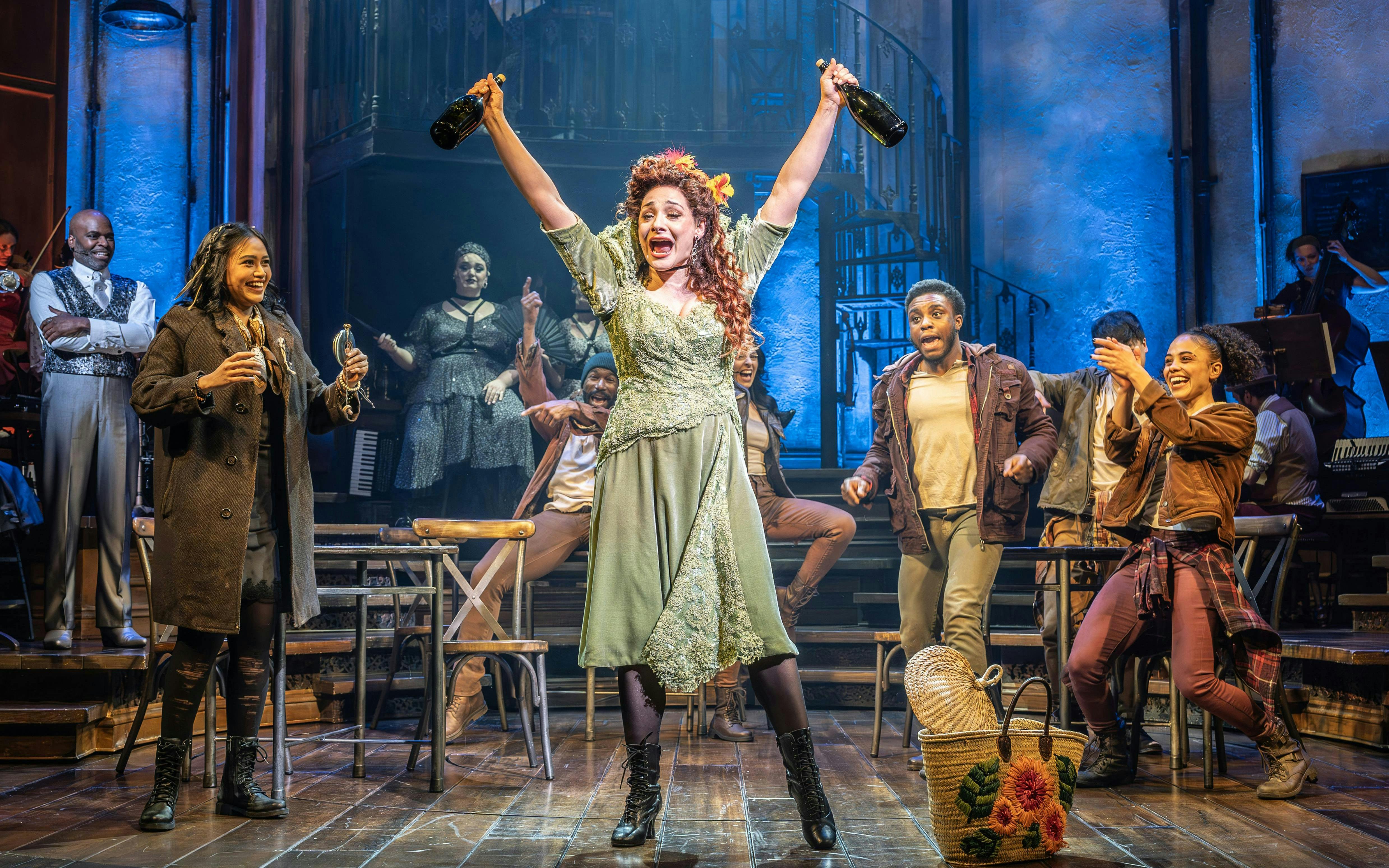 Stage performance of Hadestown in West End with actors celebrating on stage.