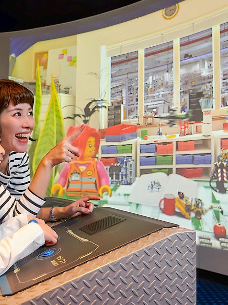 Child and adult enjoying interactive Lego display at Legoland Kansai.