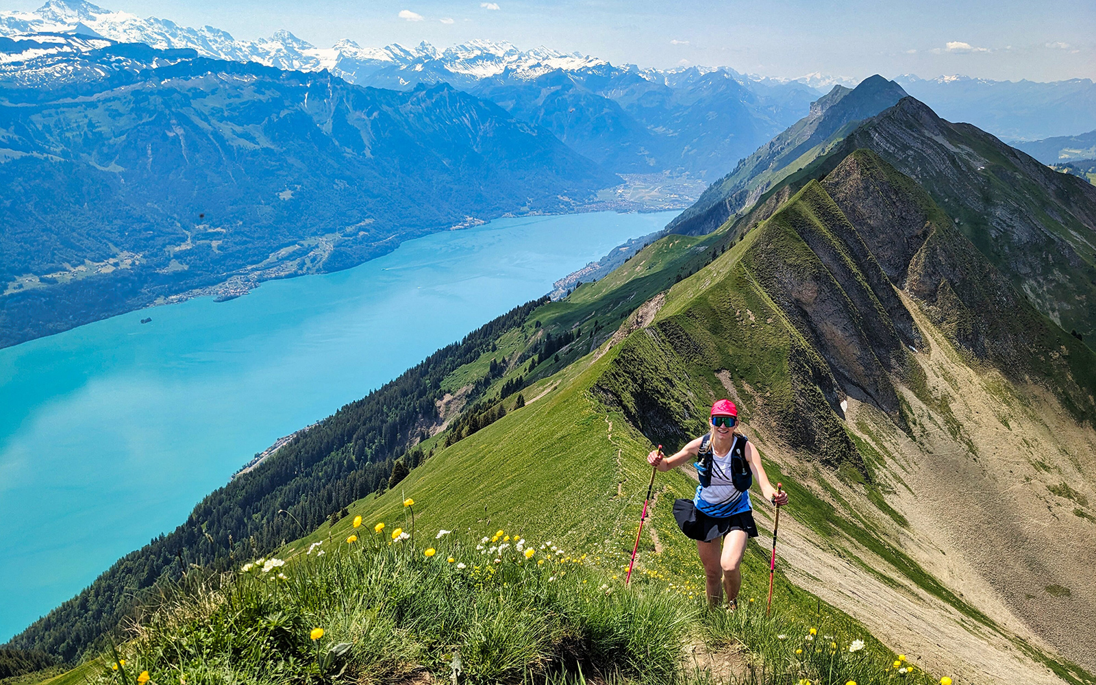 Hiker on a mountain trail overlooking Lake Brienz and the Swiss Alps.