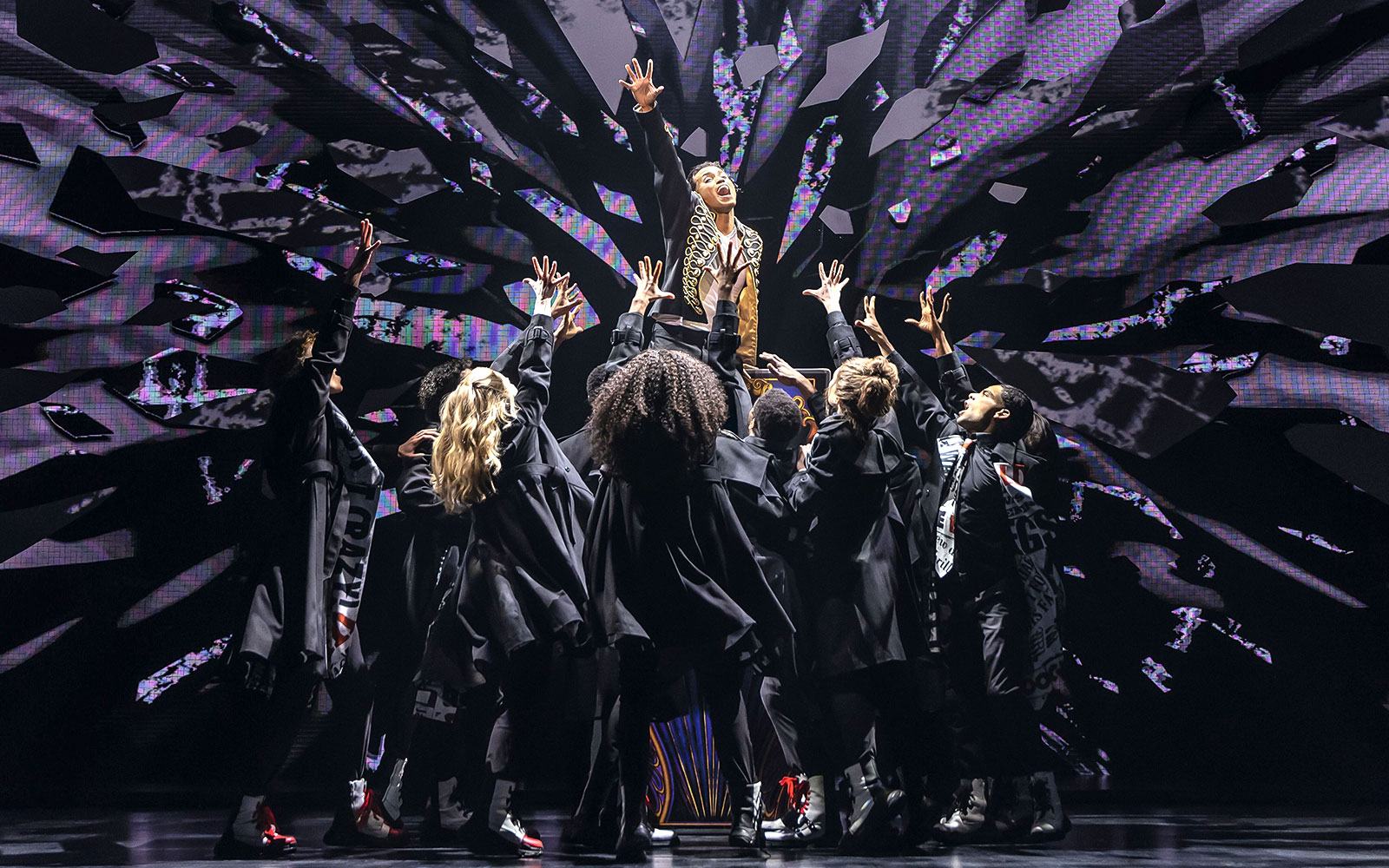 Performers on stage during MJ Das Musical, reaching towards a central figure.