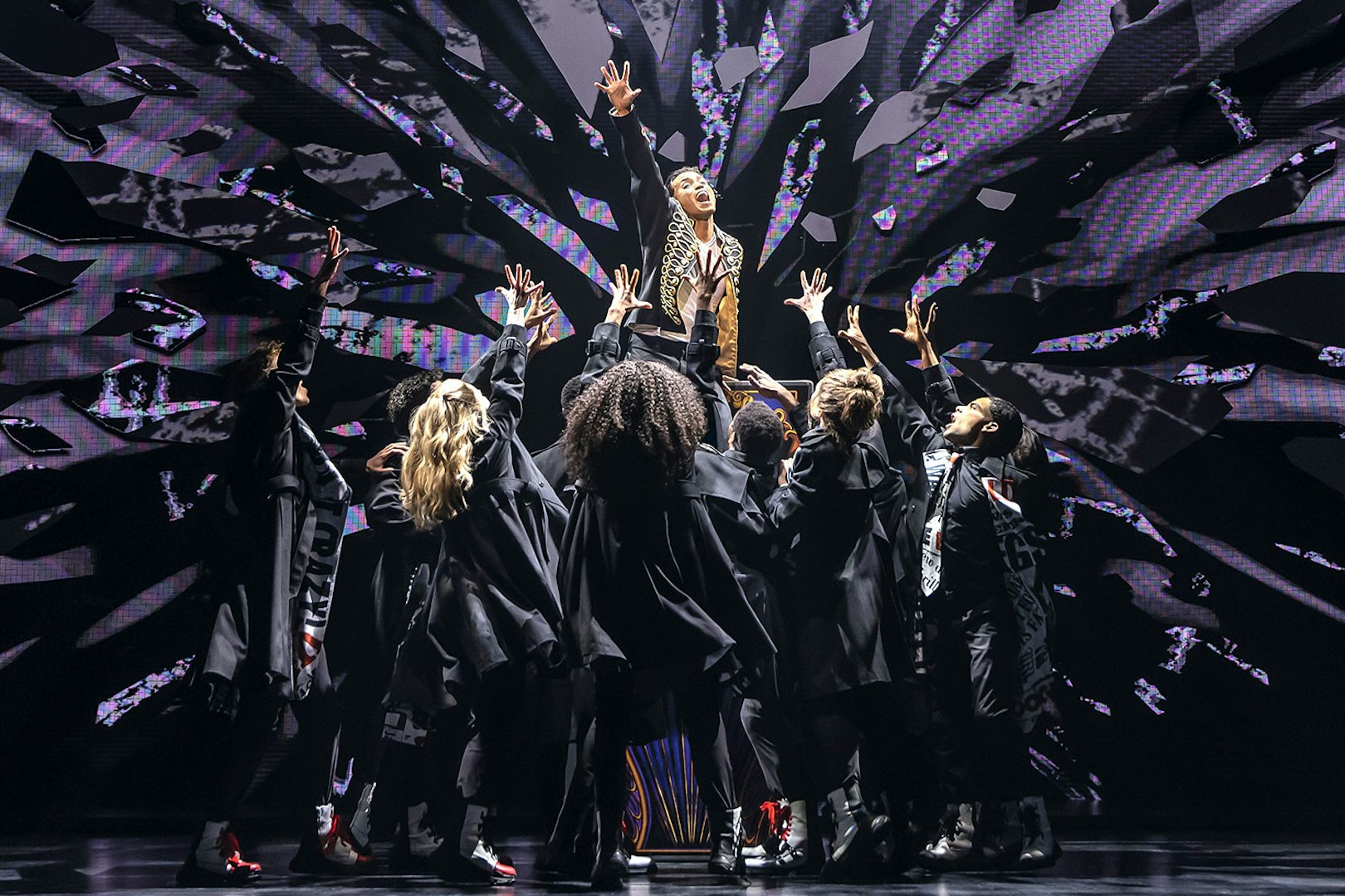 Performers on stage during MJ Das Musical, reaching towards a central figure.