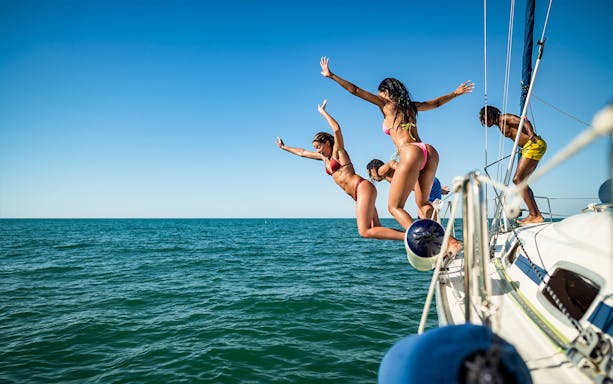 People diving from a boat into the turquoise waters of Capri.
