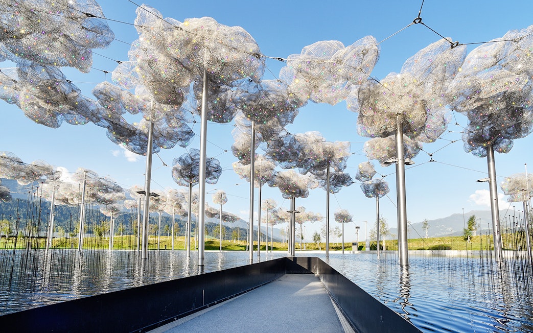 Swarovski Crystal Worlds outdoor installation with reflective water and mountain backdrop.