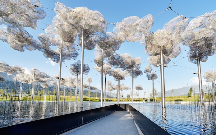 Swarovski Crystal Worlds outdoor installation with reflective water and mountain backdrop.