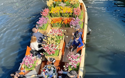 Guests enjoying tulip display on luxury cruise in Amsterdam canal.