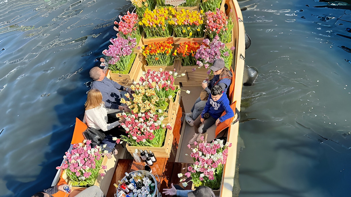Guests enjoying tulip display on luxury cruise in Amsterdam canal.