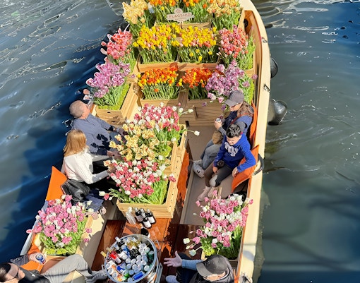 Guests enjoying tulip display on luxury cruise in Amsterdam canal.