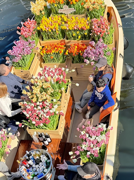 Guests enjoying tulip display on luxury cruise in Amsterdam canal.