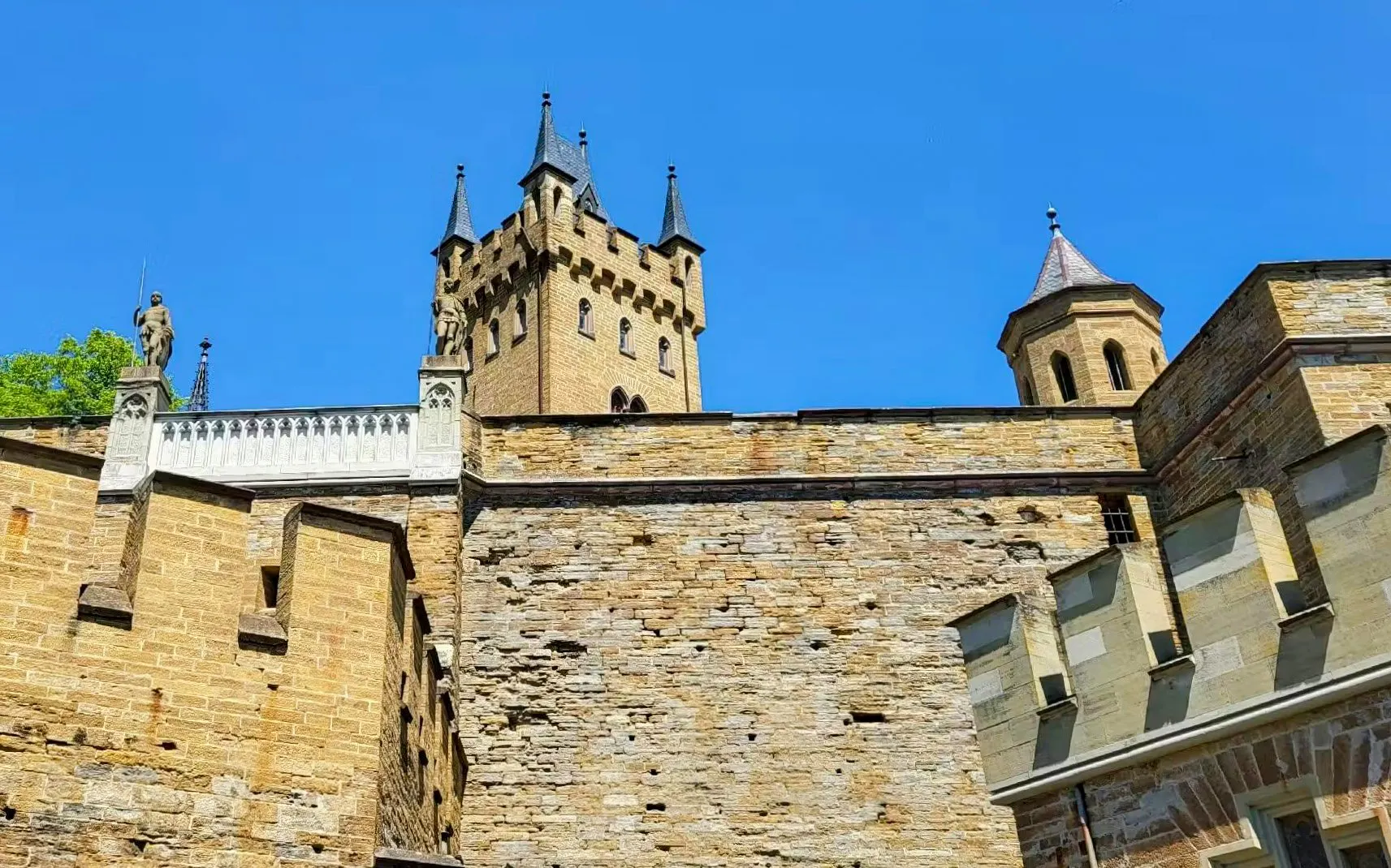 Hohenzollern Castle's stone walls and towers under a clear blue sky, Germany.