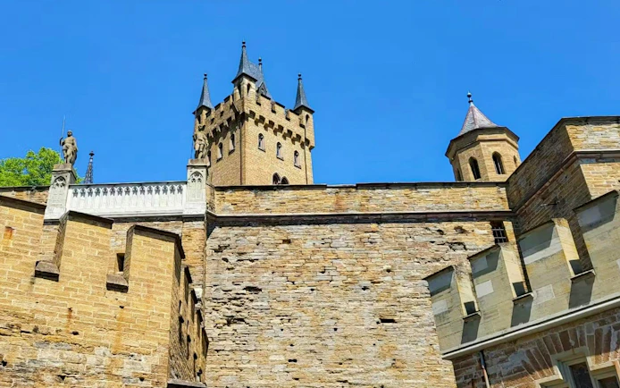 Hohenzollern Castle's stone walls and towers under a clear blue sky, Germany.