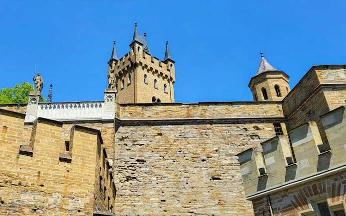 Hohenzollern Castle's stone walls and towers under a clear blue sky, Germany.