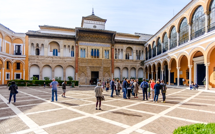 Tourists exploring the courtyard of Alcázar in Seville.