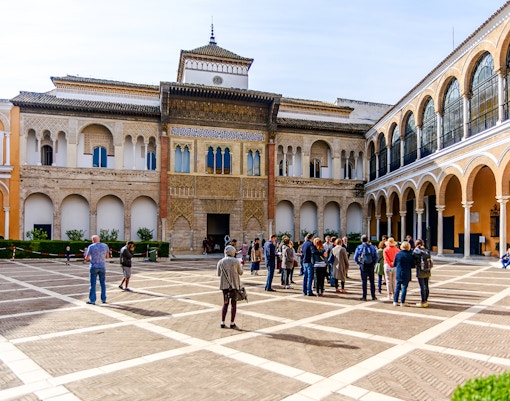 Tourists exploring the courtyard of Alcázar in Seville.