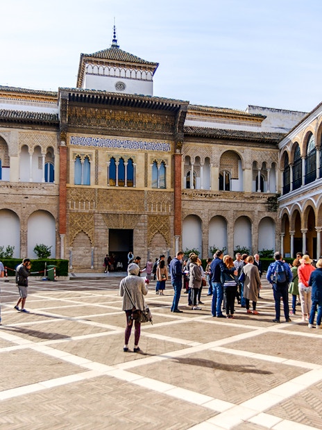 Tourists exploring the courtyard of Alcázar in Seville.
