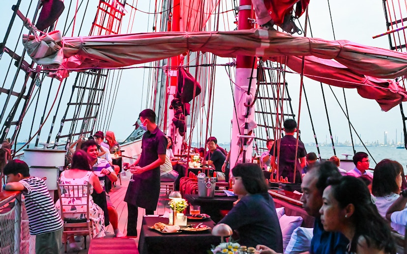 Guests dining on a luxury tall ship cruising Singapore's waters.