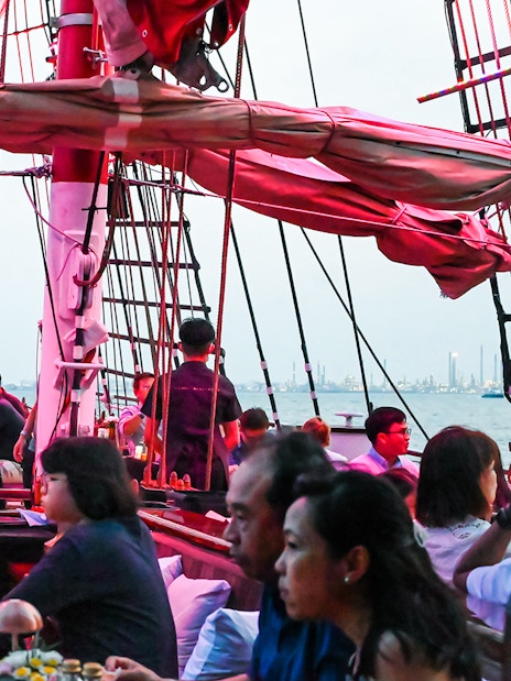 Guests dining on a luxury tall ship cruising Singapore's waters.