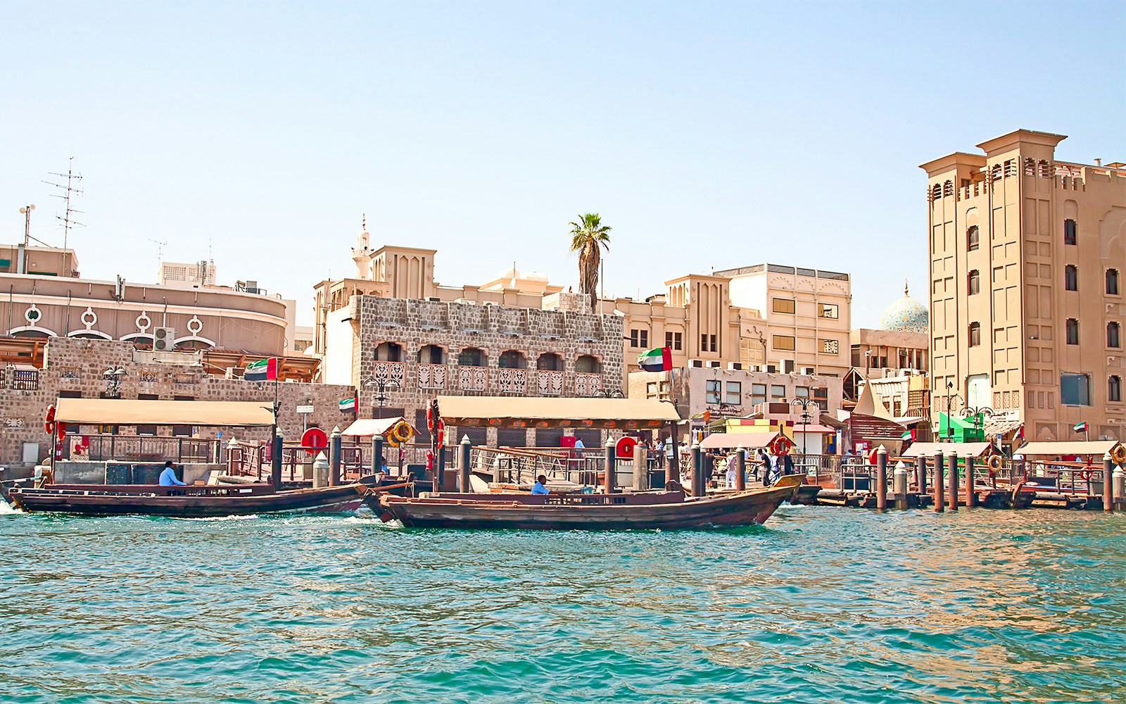 Dubai Creek with traditional abras and historic buildings on a sightseeing tour.