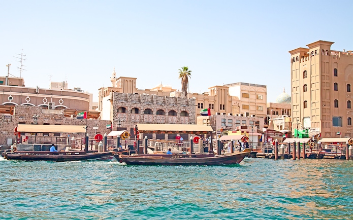 Dubai Creek with traditional abras and historic buildings on a sightseeing tour.