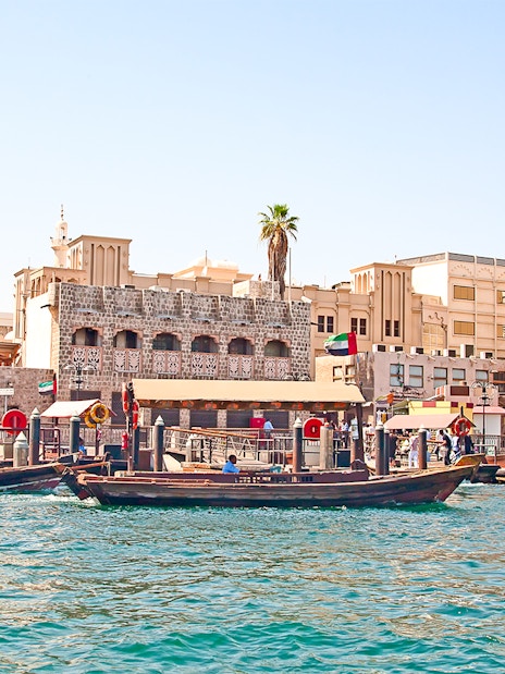 Dubai Creek with traditional abras and historic buildings on a sightseeing tour.