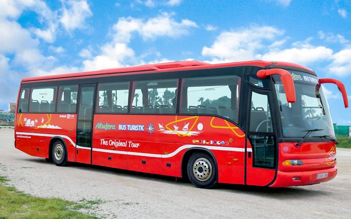 Red tour bus at Albufeira Natural Park, Portugal, offering scenic rides and boat tours.